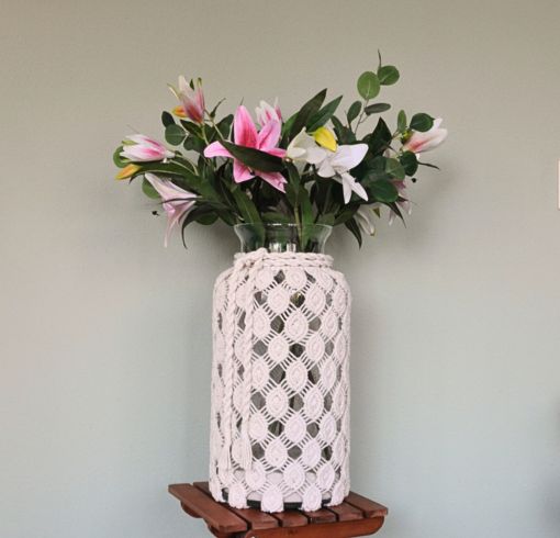 grote glazen vaas met macrame van licht garen. Bevat kunstbloemen